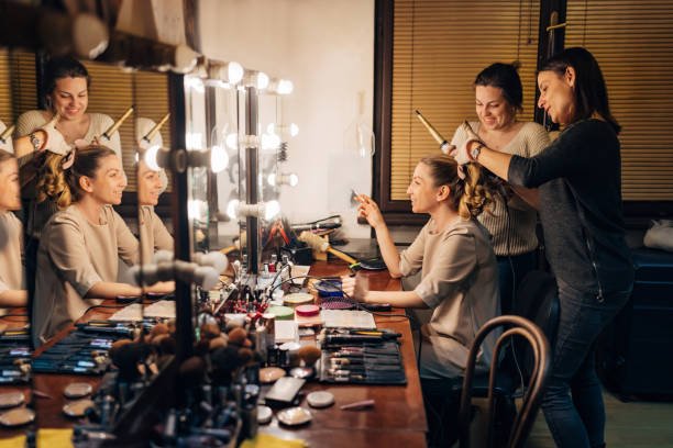 Two hairdressers are doing the hair of a theater actress in the theater backstage